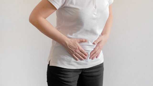 Una mujer se siente el abdomen