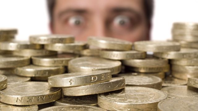 Hombre mirando monedas de libras esterlinas