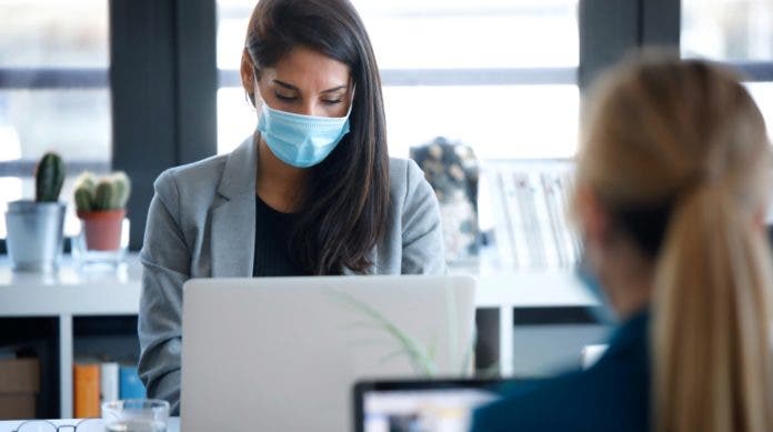 Two business women wearing a hygienic face mask while work with