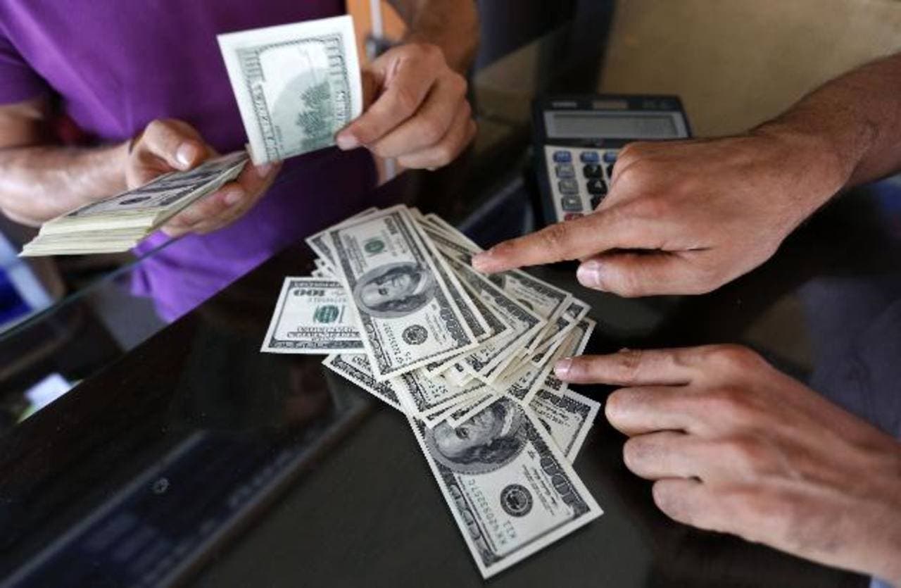A money changer sells U.S. dollars to a customer in the border city of Hatay