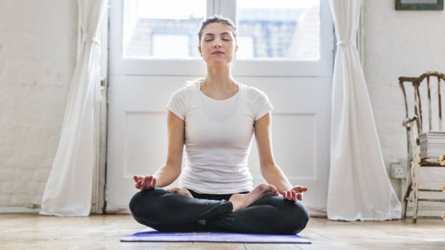 Una mujer sentada en la postura de yoga conocida como posición de loto