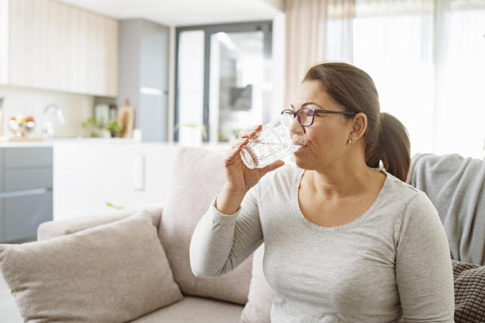 Mujer tomando agua de un vaso de cristal