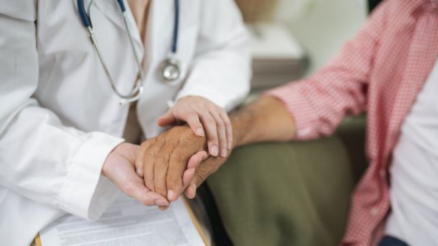 Una doctora le toma la mano a una paciente con párkinson