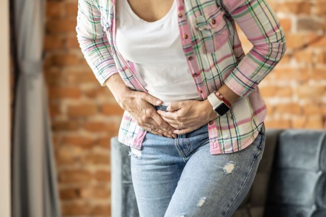 Mujer se agarra el abdomen y se lo aprieta. 